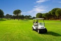 Golf cart on a golf course with green grass field with blue sky and trees in Belek, Turkey Royalty Free Stock Photo