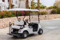 The Golf cart is parked next to a flower bed. The electric car is located near the tourist hotel. There is an empty pleasure car Royalty Free Stock Photo