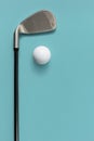 Golf club and golf ball isolated on light turquoise blue background