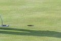 Golf club in front of the hole and the shadow of a person on the grass Royalty Free Stock Photo