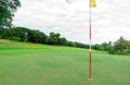 Golf course with green turf landscape. Green grass field with yellow golf flag pole. Golf course at hotel or resort. Landscape of Royalty Free Stock Photo