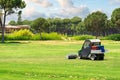 Golf course and a vehicle collecting golf balls. Ballpicker on driving range of golf club Royalty Free Stock Photo