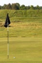 Golf green with flag pole and ball in foreground Royalty Free Stock Photo