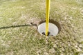 Golf hole with yellow stick and green grass