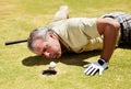 Golf, man and blowing ball into hole on a grass field for player match and putting. Fitness, sport and funny mature male Royalty Free Stock Photo