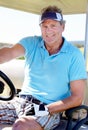 Golf is my favourite passtime. A happy mature man smiling while sitting in a golf cart.