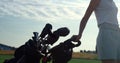 Golf person taking clubs bag trolley in country club. Woman walk golfing course. Royalty Free Stock Photo