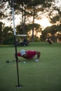 Golf player blowing ball in hole with sunset in background Royalty Free Stock Photo