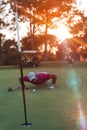 Golf player blowing ball in hole with sunset in background Royalty Free Stock Photo