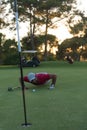 Golf player blowing ball in hole with sunset in background Royalty Free Stock Photo