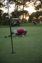 Golf player blowing ball in hole with sunset in background Royalty Free Stock Photo