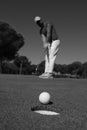 Golf player hitting shot, ball on edge of hole