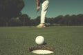 Golf player hitting shot, ball on edge of hole