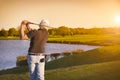 Golf player teeing-off at sunset. Royalty Free Stock Photo