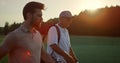 Golf players looking sunset on summer field. Golfers group walk course fairway. Royalty Free Stock Photo