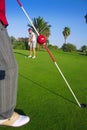 Golf woman putting gol ball and man holds flag Royalty Free Stock Photo