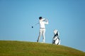 Golfer asia man approach on tee off for swing and hitting golf ball on slope green and looking fairway Royalty Free Stock Photo