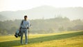 Golfer asian man walking in fairway with bag golf with club in sunlight Royalty Free Stock Photo