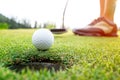 Golfer asian woman putting golf ball on the green golf on sun set evening time. Royalty Free Stock Photo