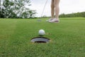 Golfer asian woman sporty putting golf ball into hole on the green golf Royalty Free Stock Photo
