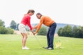 Golfer giving training to woman for taking a shot