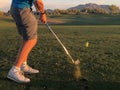 Golfer hitting a golf ball from a back view.