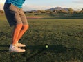 Golfer hitting a golf ball from a back view.