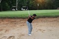 Golfer hitting golf ball on bunker of sand in course Royalty Free Stock Photo