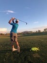 Golfer hitting a golf balls for practice from a back view.