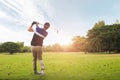 Golfer hitting golf shot with club on course at evening time. Royalty Free Stock Photo