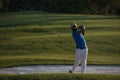 Golfer hitting a sand bunker shot on sunset Royalty Free Stock Photo