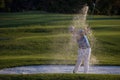 Golfer hitting a sand bunker shot on sunset