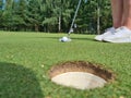 Golfer on lawn hits ball into hole in hole Royalty Free Stock Photo
