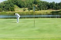 Golfer man playing golf aiming shot for putting ball on the hole with club on green course. Royalty Free Stock Photo