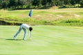 Golfer man playing golf aiming shot for putting ball on the hole with club on green course. Royalty Free Stock Photo