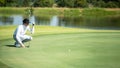 Golfer man playing golf aiming shot for putting ball on the hole with club on green course. Royalty Free Stock Photo