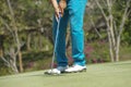 Golfer putting ball on the green golf, lens flare on sun set evening time. Golfer action to win after long putting golf ball in to Royalty Free Stock Photo