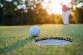 Golfer putting ball on the green golf, lens flare on sun set evening time. Golfer action to win after long putting golf ball in to Royalty Free Stock Photo