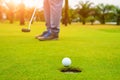 Golfer putting golf ball on the green golf, lens flare on sun set evening time, Pro Golf long putting golf ball in to the hole, su Royalty Free Stock Photo