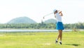 Golfer sport course golf ball fairway. People lifestyle woman playing game golf and hitting go on green grass river and mountain b Royalty Free Stock Photo