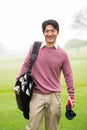 Golfer standing holding his golf bag smiling at camera Royalty Free Stock Photo