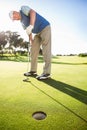 Golfer standing on the putting green watching hole