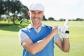 Golfer standing and swinging his club smiling at camera Royalty Free Stock Photo