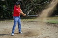 The golfer swings her golf club in a shot out of bunker sand Royalty Free Stock Photo