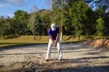 The golfer swings her golf club in a shot out of bunker sand Royalty Free Stock Photo