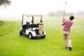 Golfer teeing off next to his golf buggy Royalty Free Stock Photo