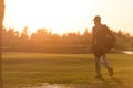 Golfer walking and carrying golf bag at beautiful sunset Royalty Free Stock Photo
