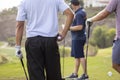 Golfers holding golf ball with golf course and golfers out of focus in the background