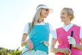 Golfing buddies with mom. Two attractive woman holding golf clubs and standing with their golf cart. Royalty Free Stock Photo