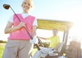 Golfing is her favorite pastime. Low angle shot of an attractive older female golfer standing in front of a golf cart Royalty Free Stock Photo